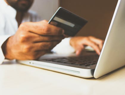 Hombre haciendo compras en una smart shop a través de su laptop con una tarjeta de crédito en la mano derecha.