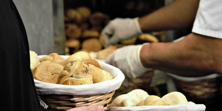 Un cliente sosteniendo dos canastas de pan en una tahona.