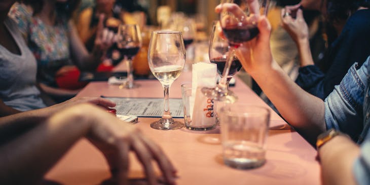 Un grupo de personas tomando vino y conviviendo en una tasca.