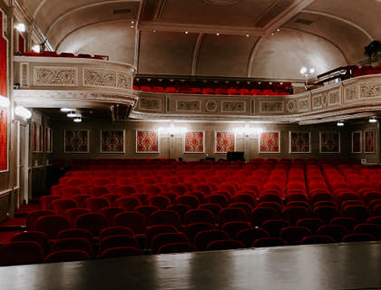 Vista de butacas rojas desde el escenario de un teatro.