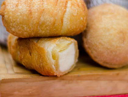 Tres tequeños apilados sobre una tabla de madera en una tequeñería.