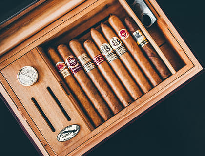 Habanos guardados dentro de un humidor sobre una superficie oscura en una tienda de humidores.