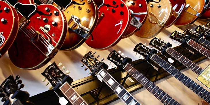 Muchas guitarras eléctricas colgadas en exhibidores en una tienda de instrumentos musicales.