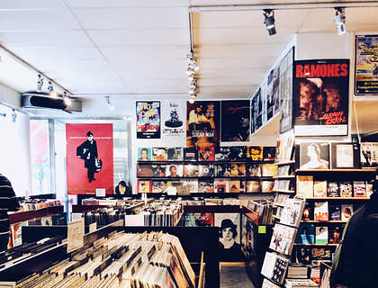El interior de una tienda de música llena de discos de vinilo, pósters e instrumentos musicales.
