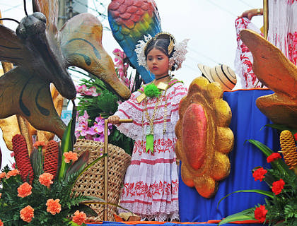 Una niña en un carro alegórico en un desfile de Panamá vistiendo un traje típico adquirido en una tienda de polleras.