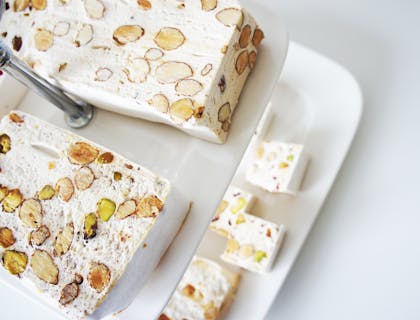 Dos platos blancos servidos con turrones en un fondo blanco en una tienda de terrones.