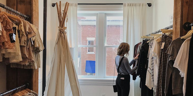 Una mujer de perfil vestida al estilo vintage en una tienda de ropa vintage.