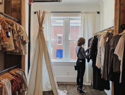 Una mujer de perfil vestida al estilo vintage en una tienda de ropa vintage.