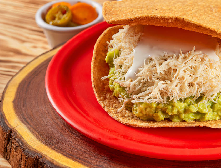 una tostada gigante de pollo, crema y aguacate en una tostadería