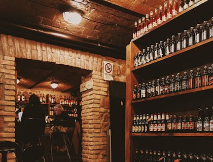 Mesas, botellas de vino y clientes dentro de una vinoteca