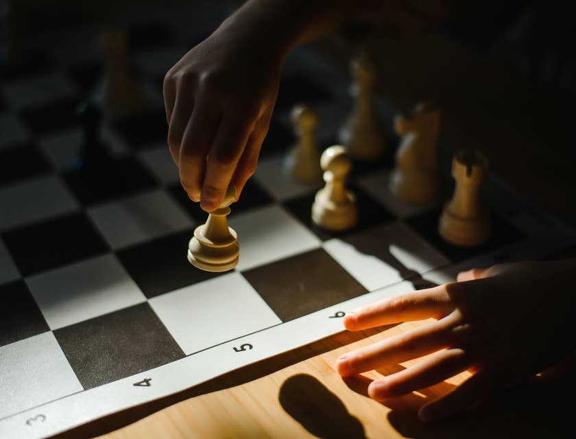 Manos de una persona sobre un tablero de ajedrez moviendo una pieza, en un negocio con nombre prodigioso.