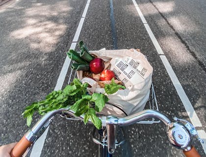 Una canasta de bicicleta llena de comida saludable por parte un negocio con nombre saludable.