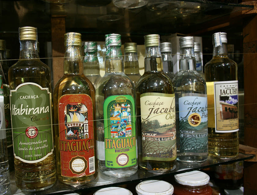 Garrafas de cachaça em cima de uma prateleira em uma cachaçaria.