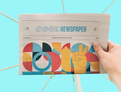 Uma pessoa segurando um jornal escolar colorido contra um fundo azul.