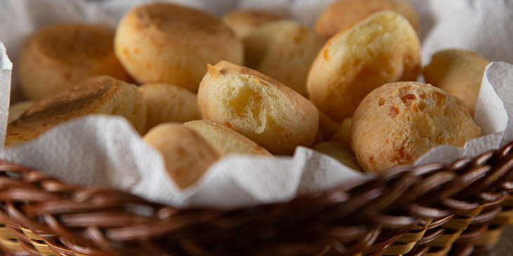 uma bandeja cheia de pães de queijo em uma loja de pão de queijo