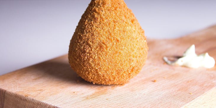Coxinha em cima de uma mesa em uma loja de salgados.