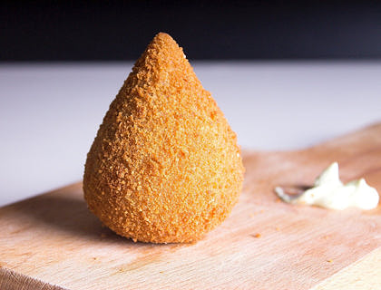 Coxinha em cima de uma mesa em uma loja de salgados.