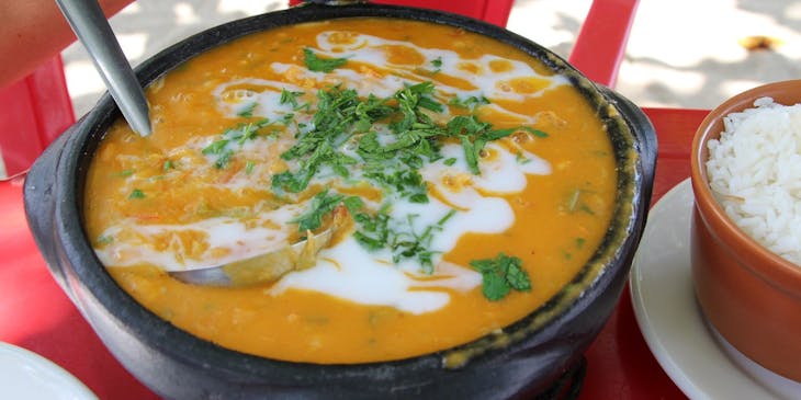 Bobó de camarão servido em uma panela de barro ao lado de uma porção de arroz em um restaurante baiano.