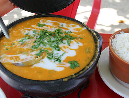 Bobó de camarão servido em uma panela de barro ao lado de uma porção de arroz em um restaurante baiano.
