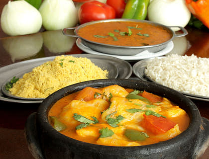 Prato de moqueca, arroz e farofa na frente de alguns temperos em um restaurante capixaba