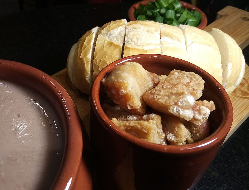 feijão, torresmo e pão em uma mesa de um restaurante de comida mineira.