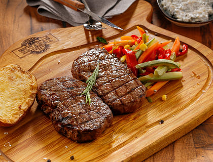 Tábua com churrasco, legumes e pão em um restaurante gaúcho