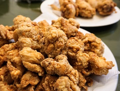 Dei bocconcini di pollo fritti su dei piatti bianchi in una friggitoria.