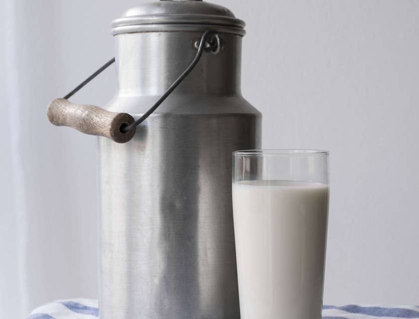 Un bicchiere di latte fresco e un bidone in alluminio per il latte.