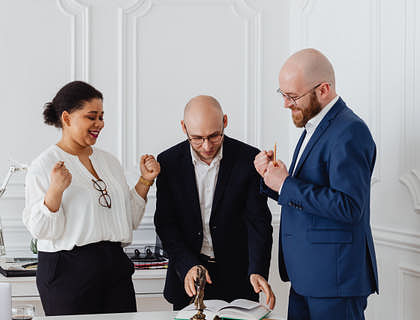 Des avocats en droit de la sécurité sociale debouts autour d'une table dans leur cabinet.