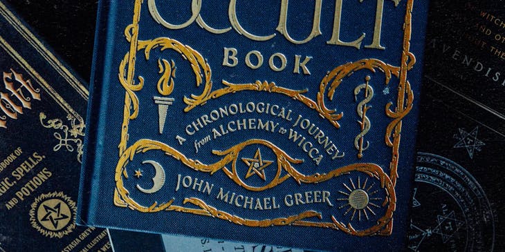 A blue, hard-cover occult book on a dark background.