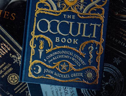 A blue, hard-cover occult book on a dark background.