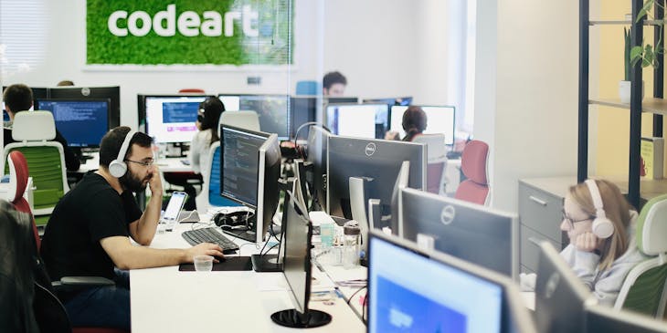 Employés assis à leur bureau portant des écouteurs.