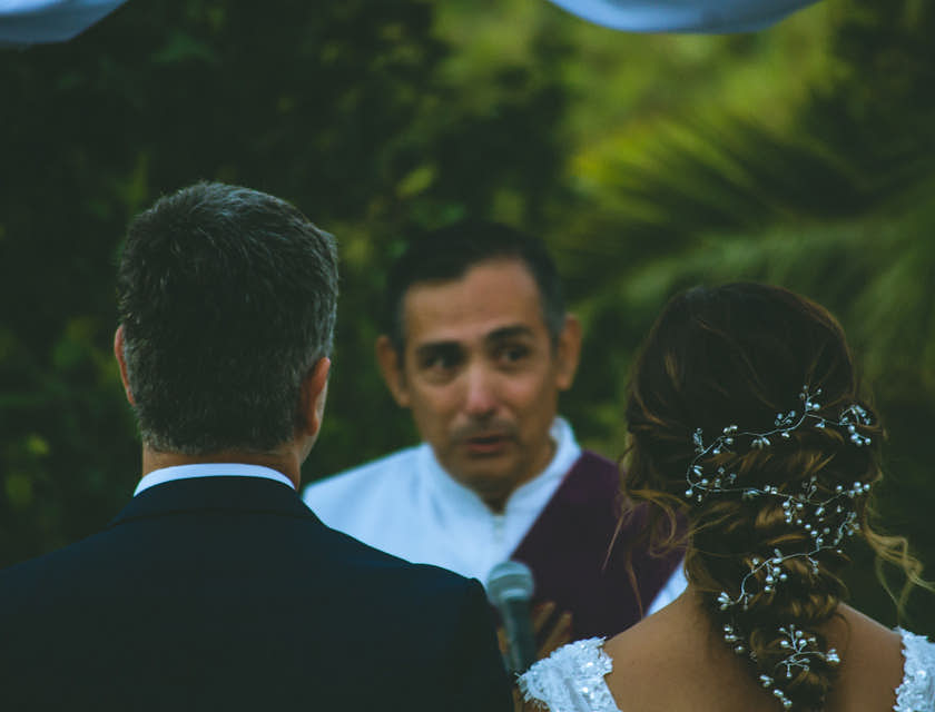 Couple de mariés se tenant devant un officiant de cérémonies.