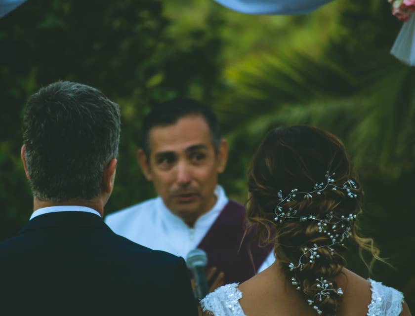 Couple de mariés se tenant devant un officiant de cérémonies.