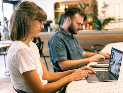Two people typing on laptops at an online business.