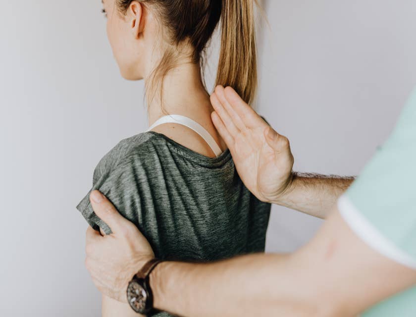 Un ostéopathe traitant une femme souffrant de douleurs dans le haut du dos.
