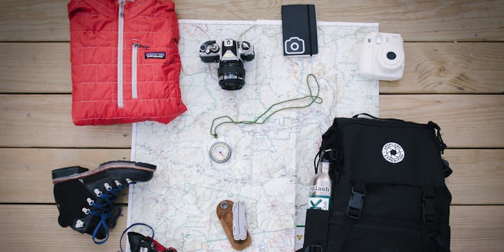 Outdoor gear and map on wooden background.