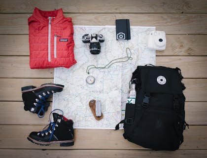 Outdoor gear and map on wooden background.
