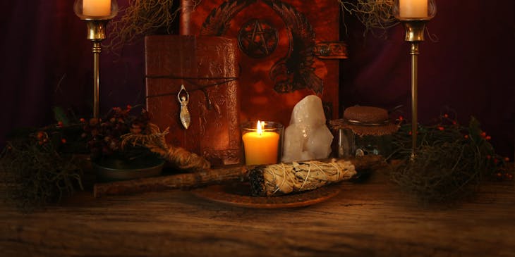 A pagan altar set with candles, spell books, crystals, and a sage wand.