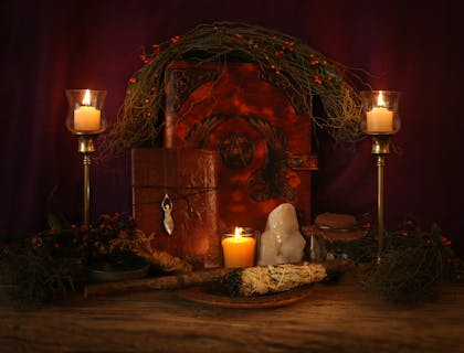 A pagan altar set with candles, spell books, crystals, and a sage wand.