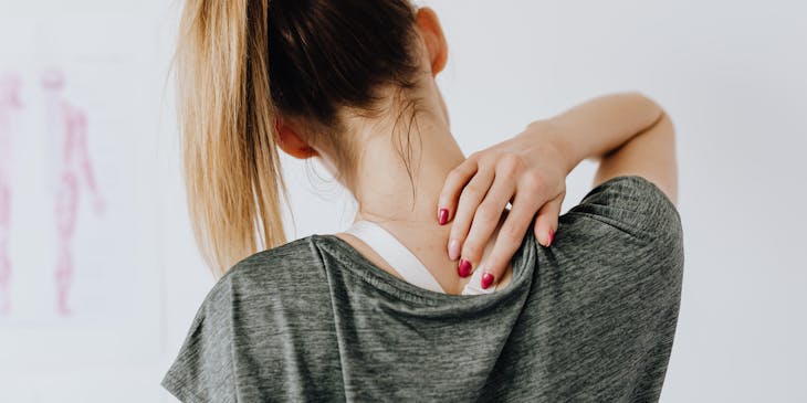 A person touching a painful spot on her back.
