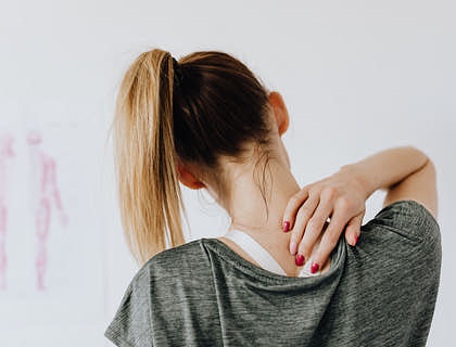 Femme touchant un point douloureux sur son dos.