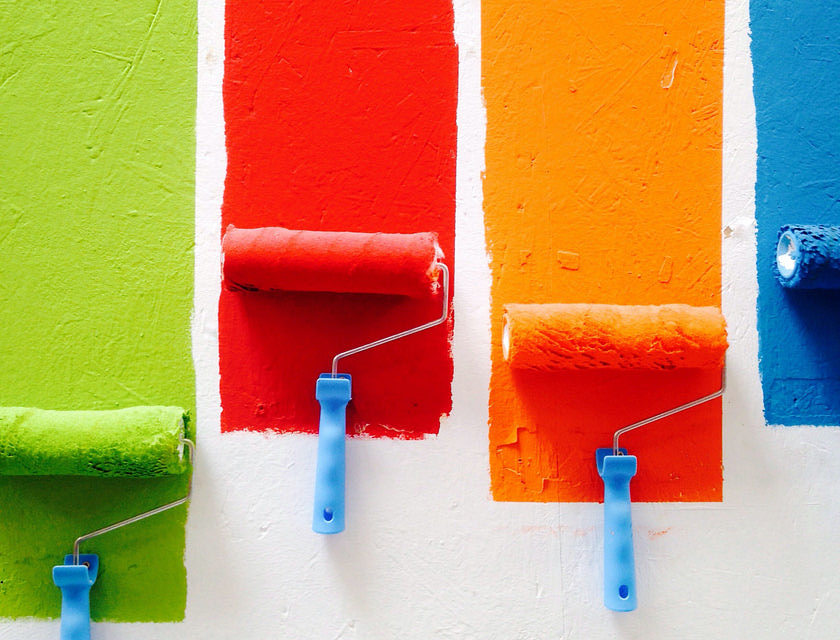 Rodillos de pintura de varios colores en la pared de un taller de pintura.