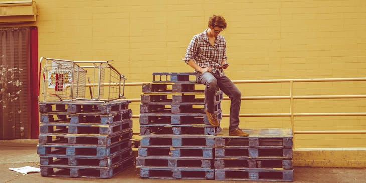 Un homme assis en haut d'une pile de palettes.