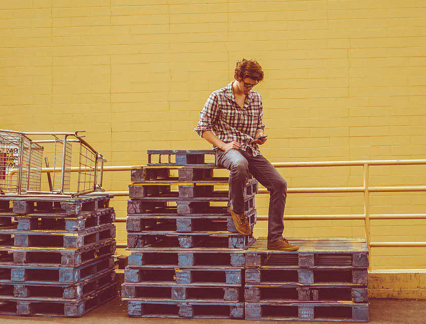 A man sitting on top of a stack of pallets.