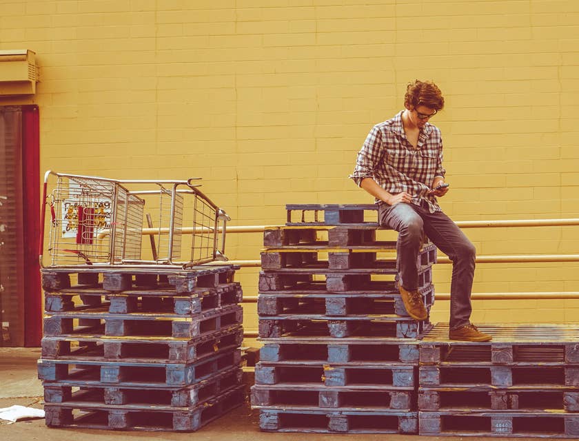 A man sitting on top of a stack of pallets.