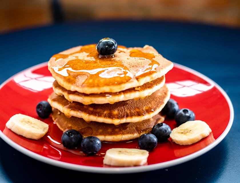 Dei pancake decorati con banane, mirtilli e sciroppo d'acero.