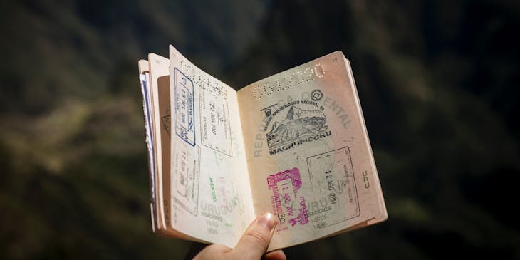 Hand holding up an open passport to show visa stamps.