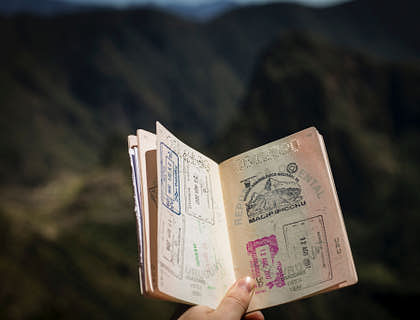 Hand holding up an open passport to show visa stamps.