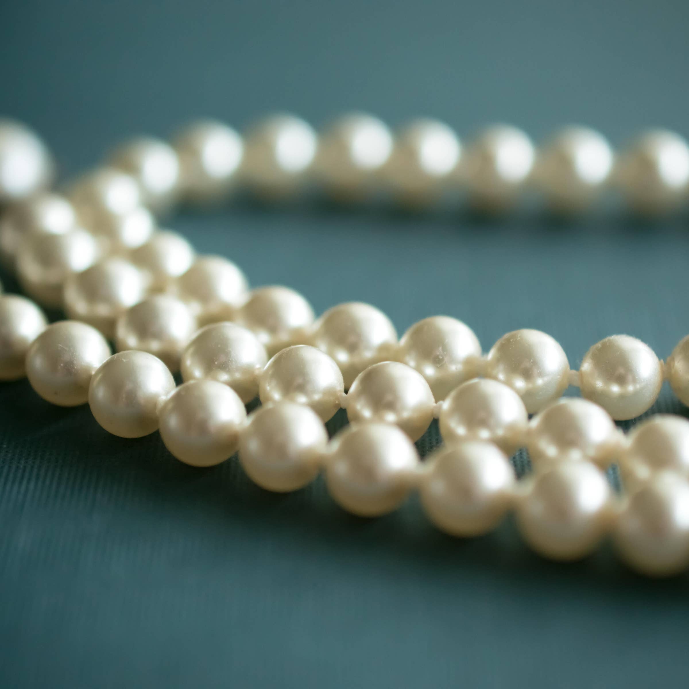 Pearls, Female hand holding string of fake pearls., style code